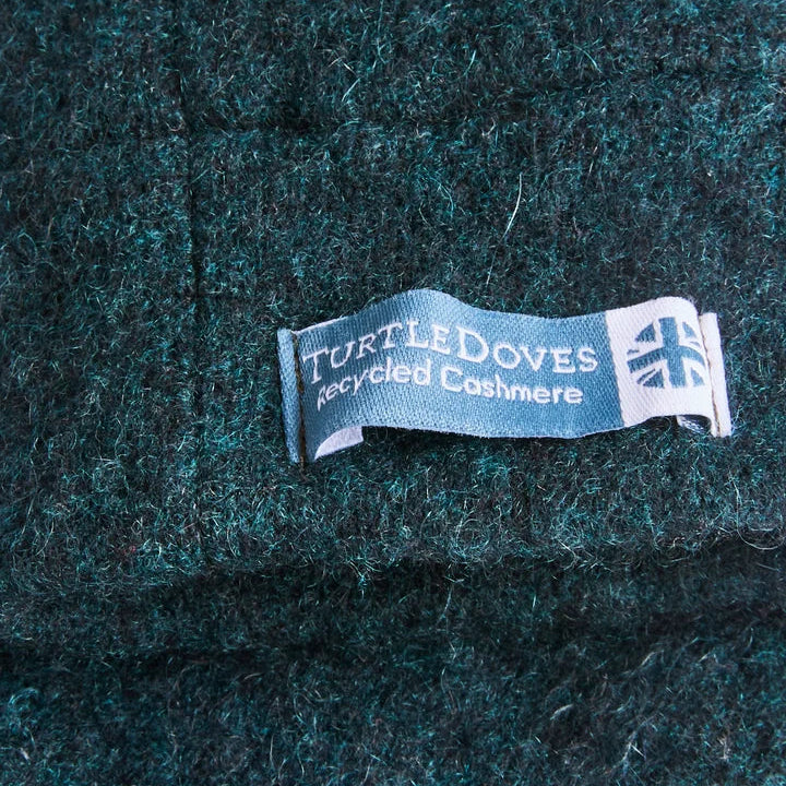 Close up of Turtle doves sewn label with recycled cashmere on green coloured glove