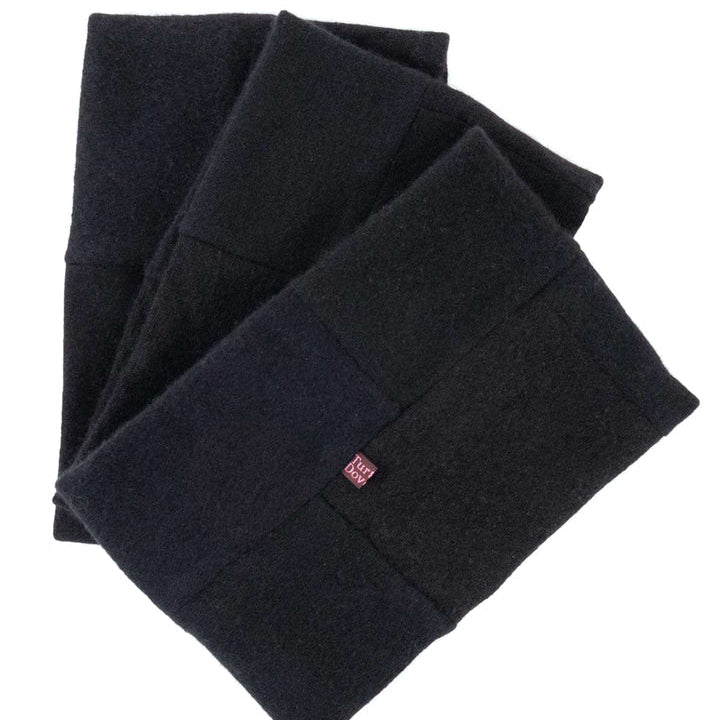 3 recycled cashmere neck warmers in tones of black on white surface with turtle doves label