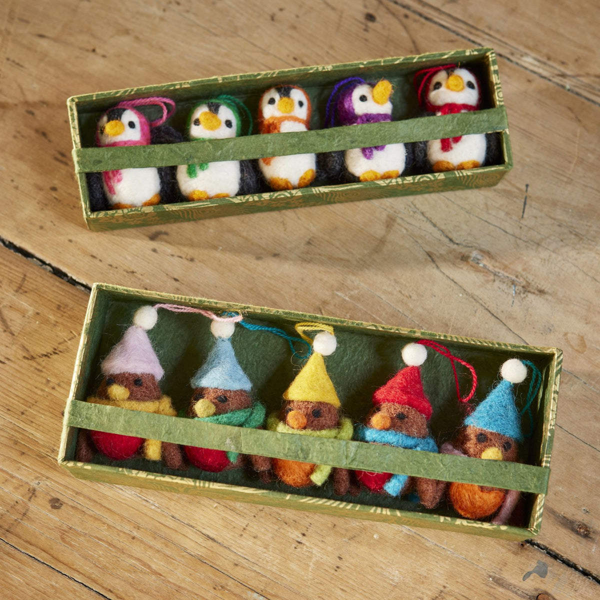 Close up of both 5 robin and 5 Penguin felt gift sets in recycled cardboard boxes and Lokta paper and ribbon wrap.