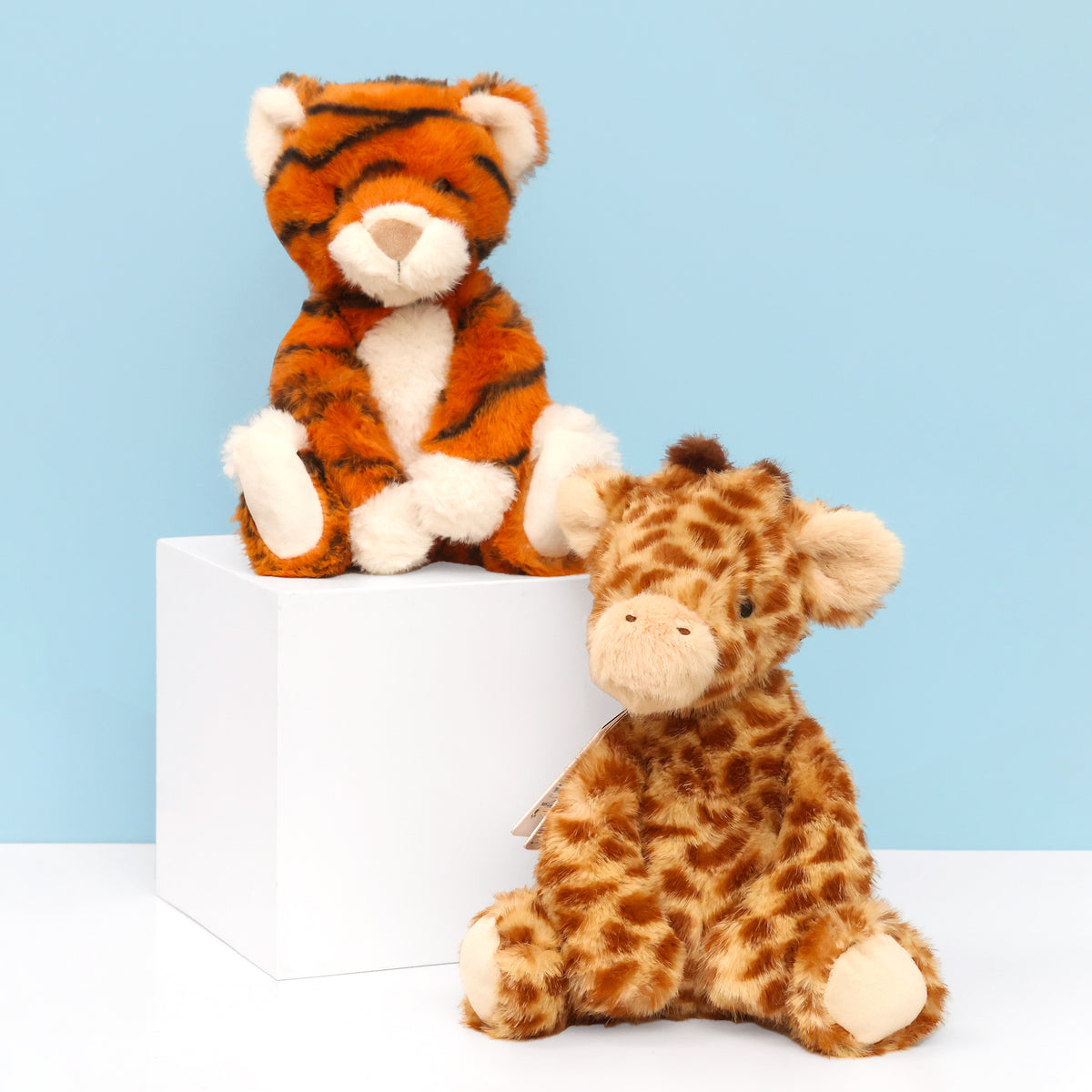 Enchanted world Tiger and Giraffe plushies sitting facing forward on white surface with blue background