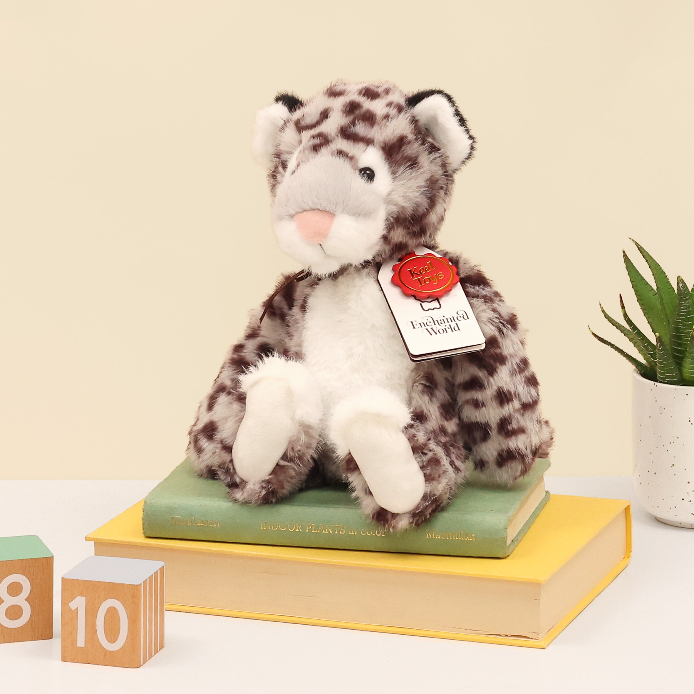 Left side of snow leopard plush made from recycled bottles, showing enchanted world and Keel toys swing tag.