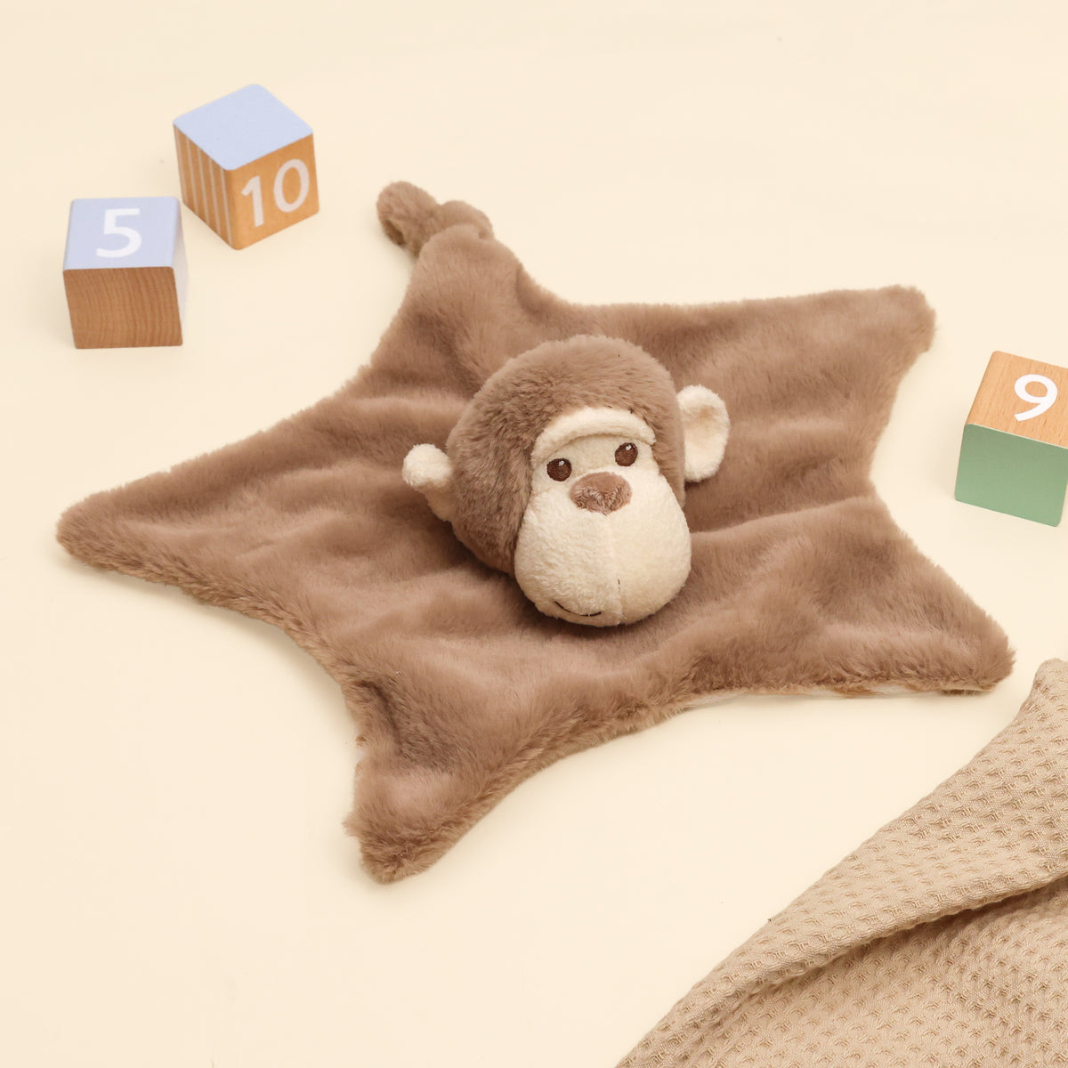 Plush Baby Marcel Monkey Blanket made from recycled bottles, in brown with wooden blocks and matching muslin on cream surface