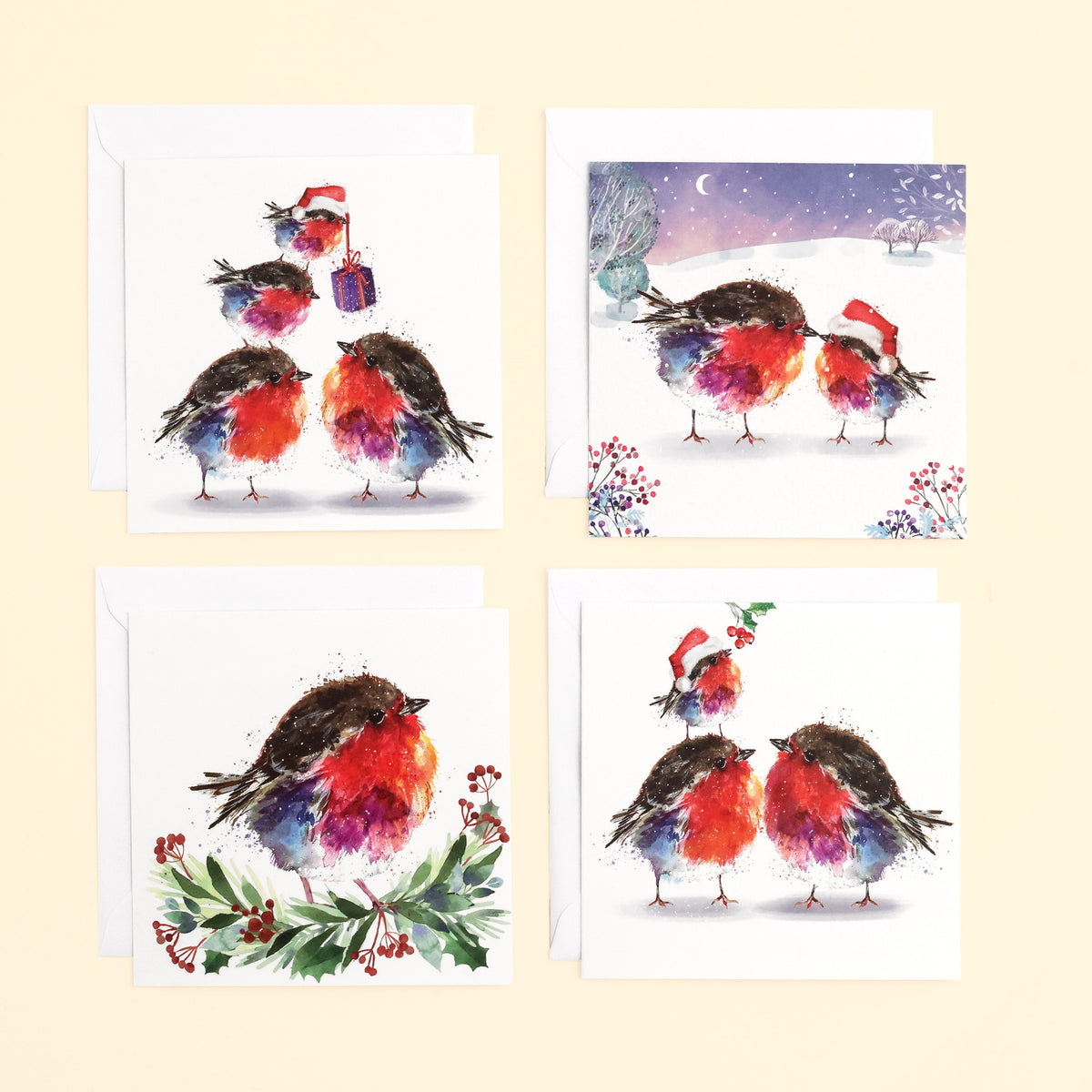 4 designs of Christmas Robins Cards; each showing a beautifully illustrated robin with their envelopes on cream background.
