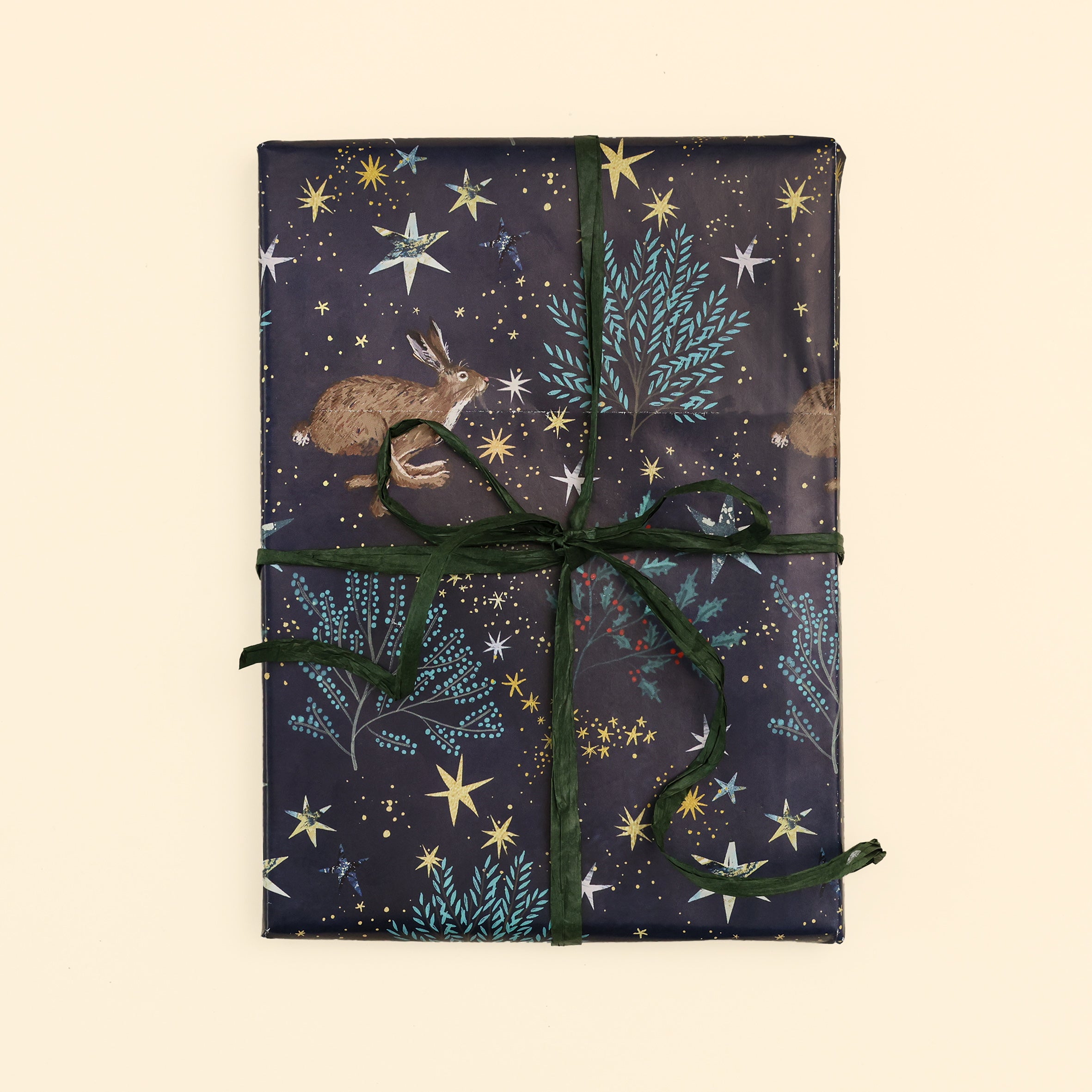 Close up of the star lit fields hare design with a wrapped gift and finished with green raffia on cream surface