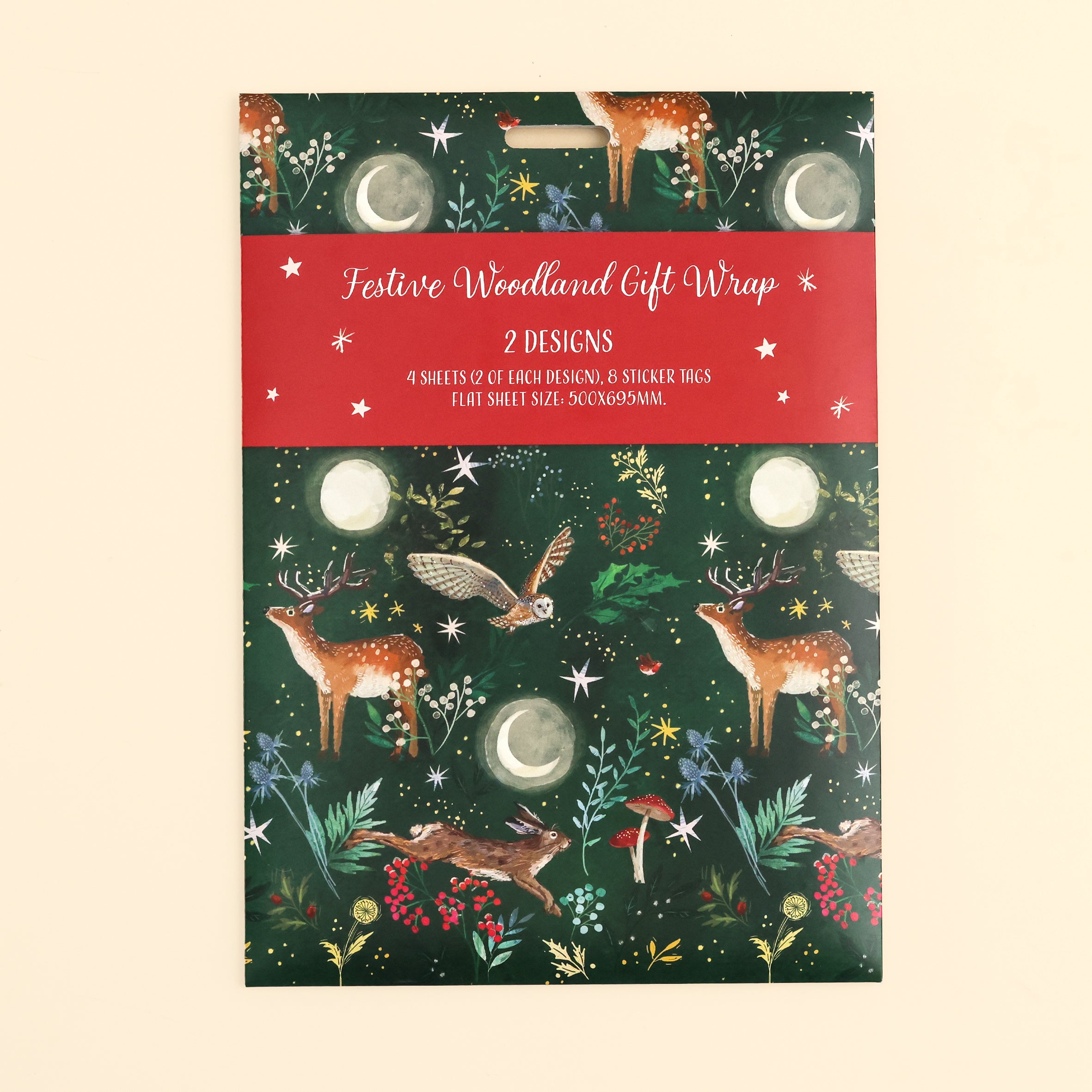 Close up of the festive woodland gift wrap pack on front with illustrated woodlands design in dark green with 4 sheets and 8 sticker tags on cream surface