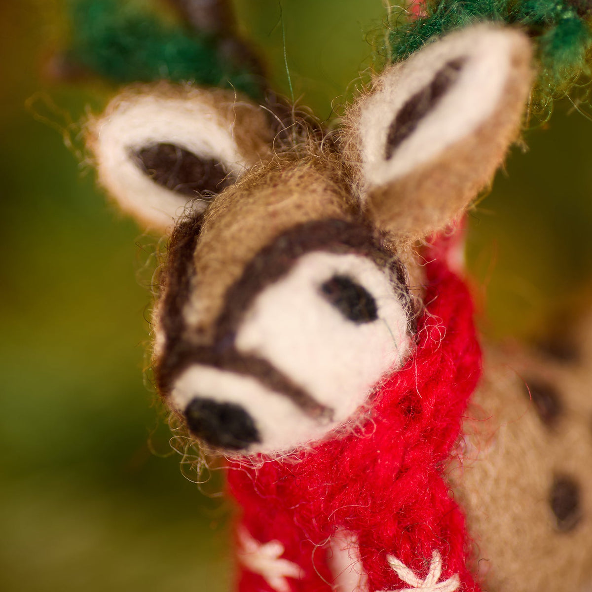Close up of reindeers face, ears and red scarf showing the embroidered stitch pattern on scarf and felt.