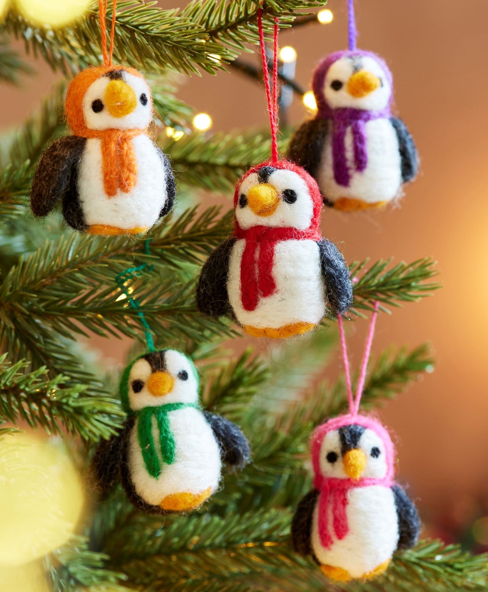 Handmade felt Penguin tree decorations hanging in tree with lights as a set