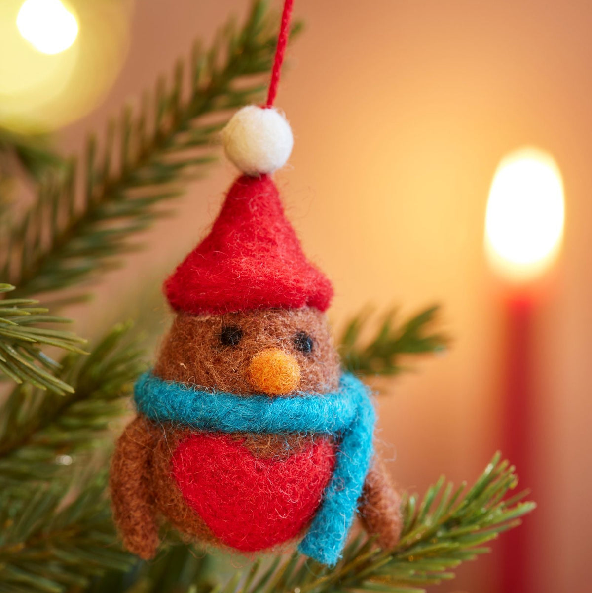 Close up of felt red robin with red hat and blue scarf hanging in tree