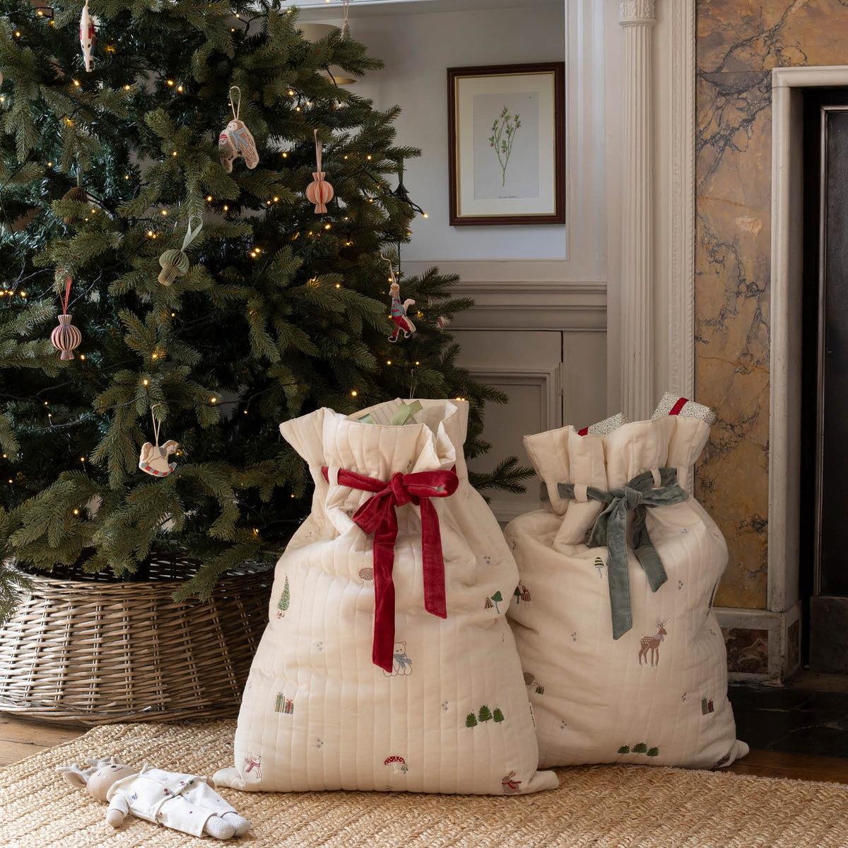 Both Reindeer and Polar bear Cotton embroidered Christmas sacks filled with gifts in front of tree