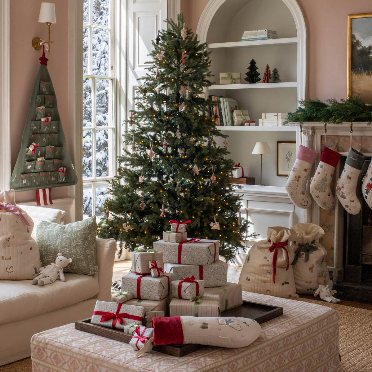 Christmas scene of a living room with stockings on the fire place, decorations on a Christmas tree and advent calendar hanging from wall with presents