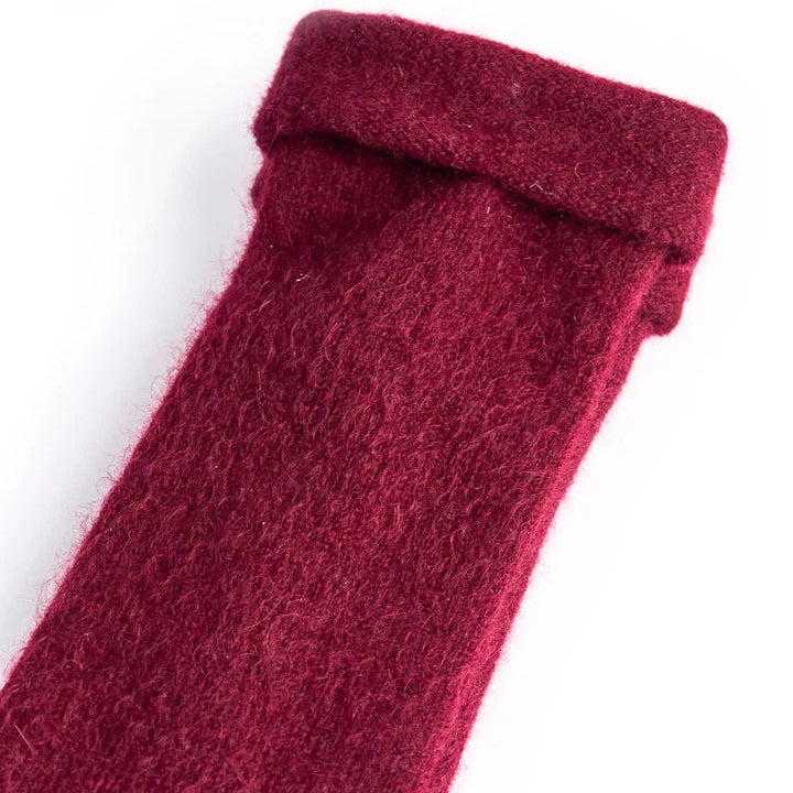 Recycled cashmere fingerless gloves in red laid on white surface