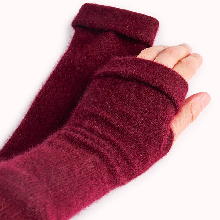 Close up of fingerless gloves in red being worn on white surface