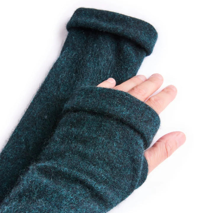Close up of hand wearing recycled cashmere glove in green on white surface