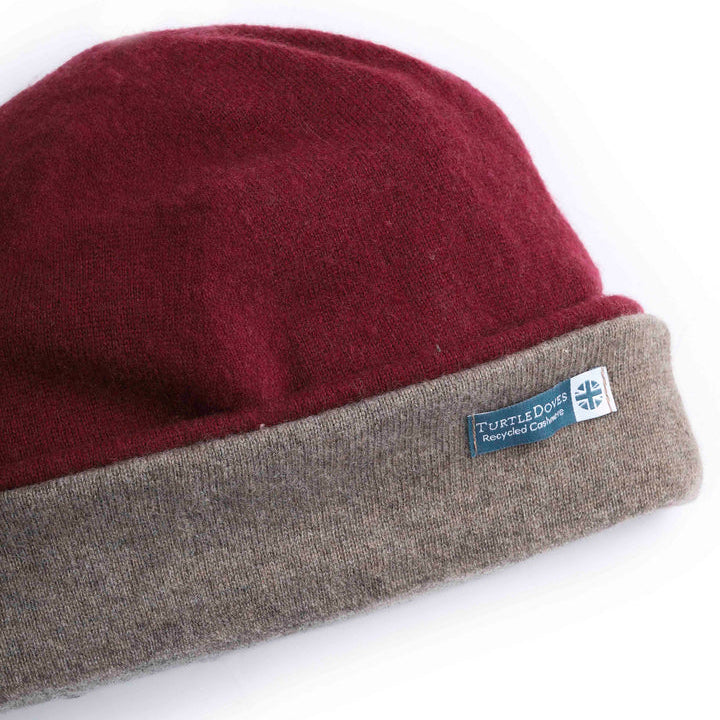 A close-up of a knit beanie hat with a deep burgundy red top section and a heather gray folded cuff. A small blue and white 'TurtleDock' brand label is stitched onto the cuff.