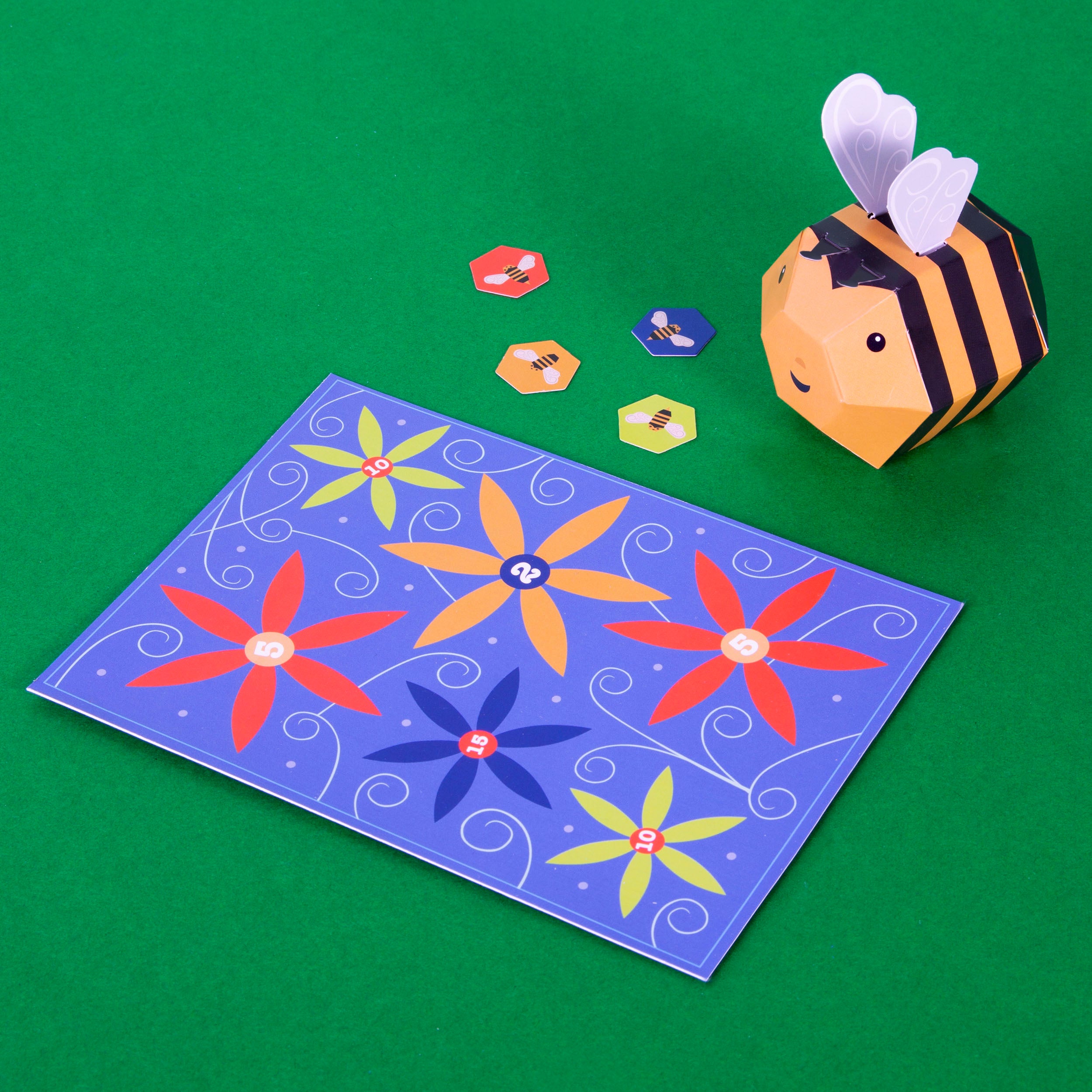cardboard bee on green surface with board game and tokens