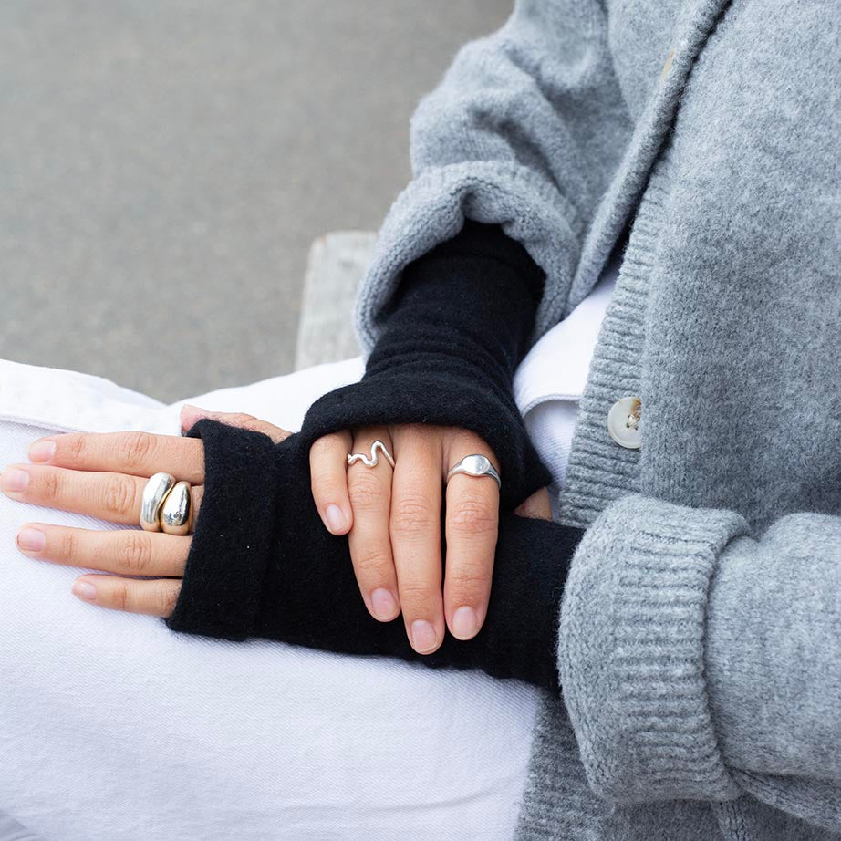 Close up of woman wearing recycled cashmere fingerless gloves in black