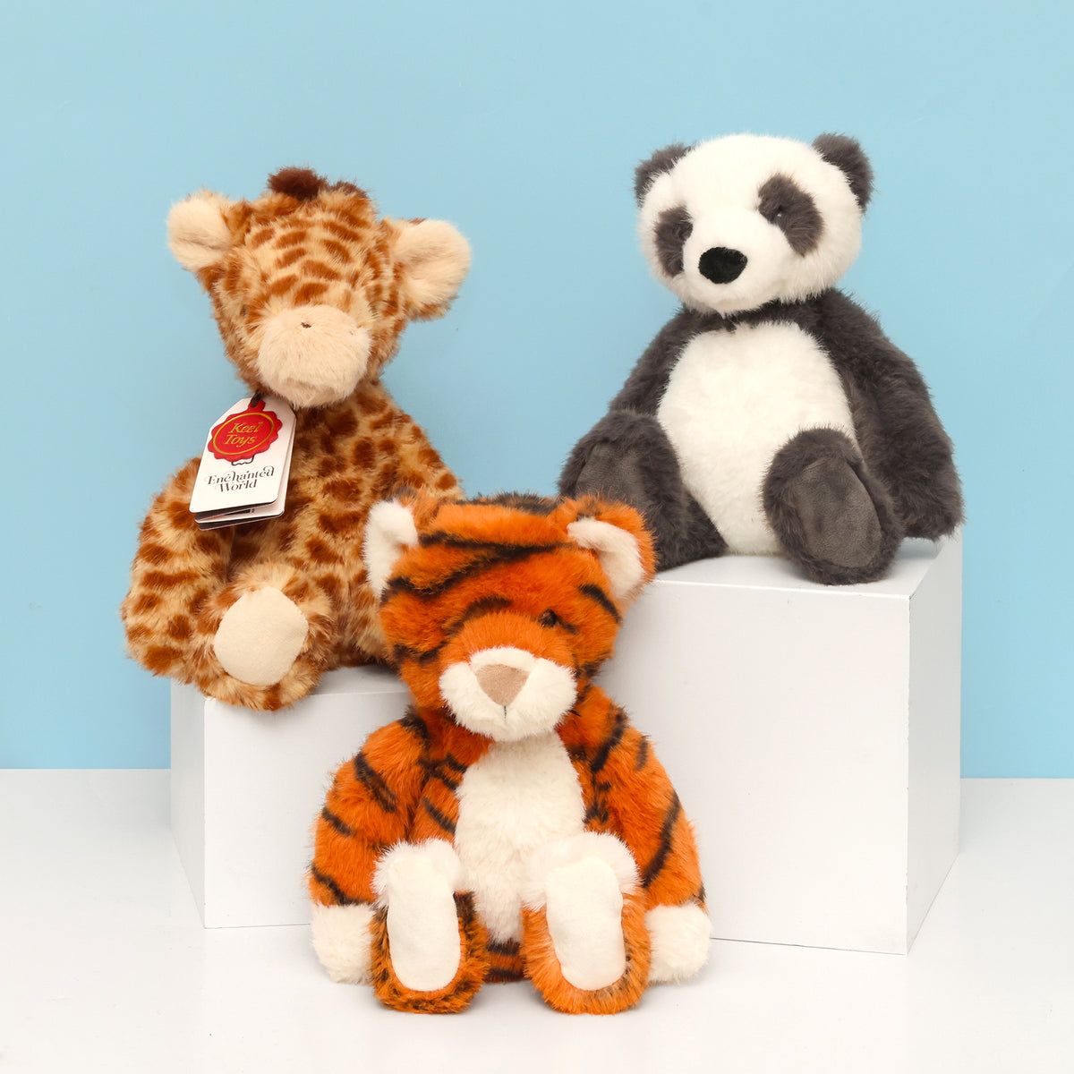 Group image of Enchanted world Panda, giraffe and tiger sitting facing forward on different height white surface with blue background