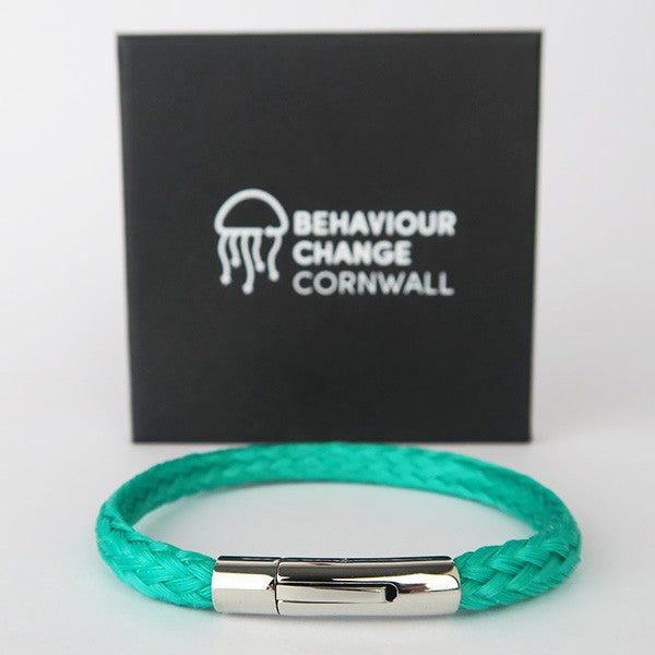 Close up of the bracelet in front of the Behaviour Change Cornwall black gift box with white logo on front