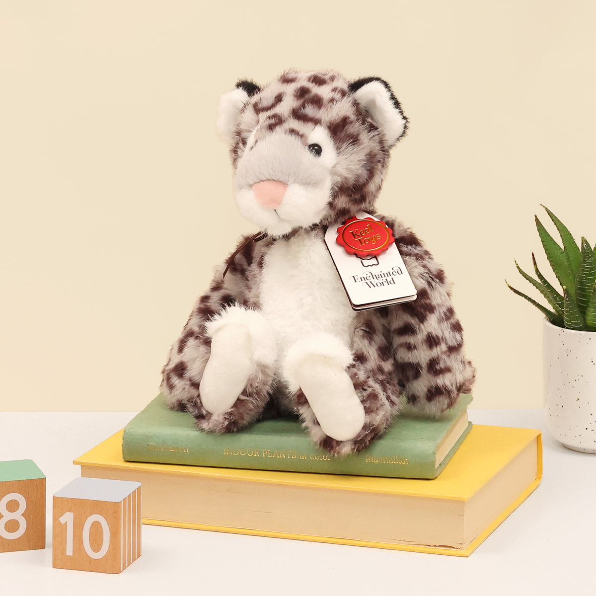 Left side of snow leopard plush made from recycled bottles, showing enchanted world and Keel toys swing tag. 