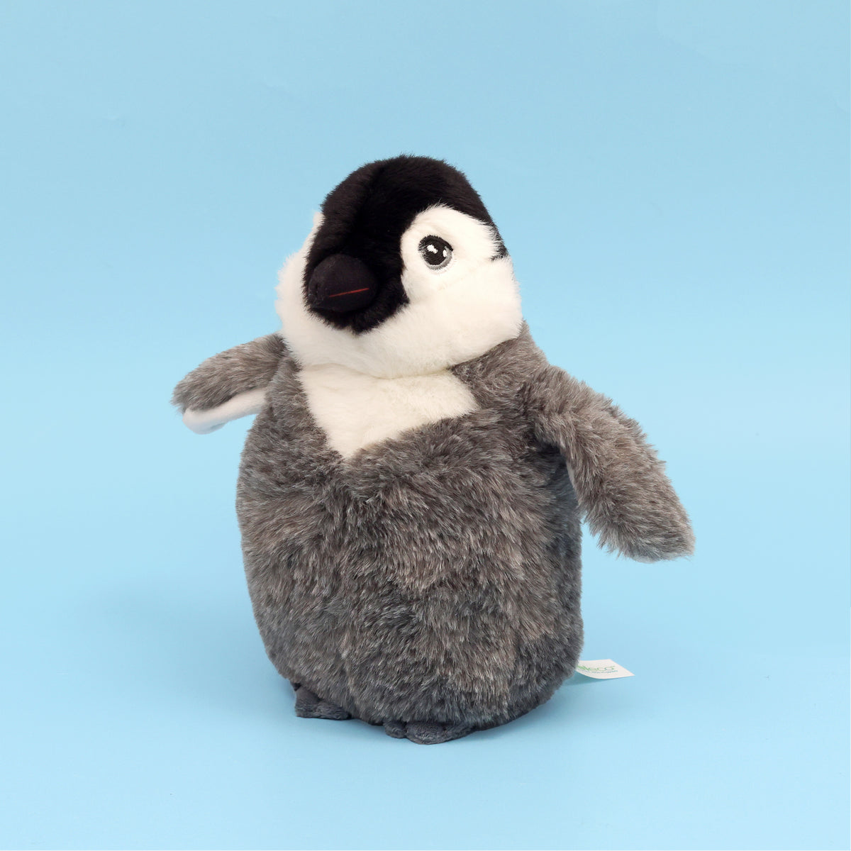 Close up of right side of Baby emperor plush penguin showing embroidered eye on blue background