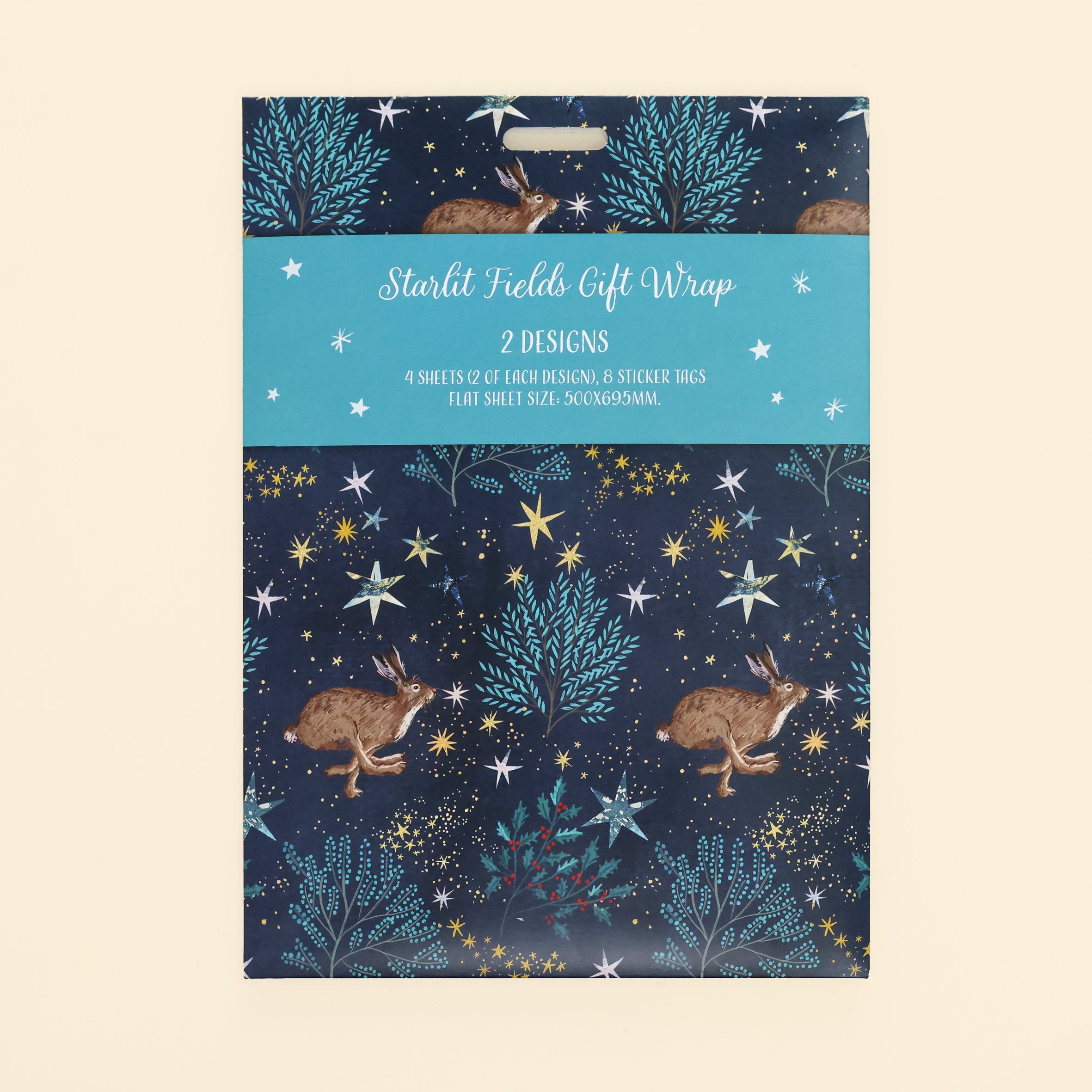 Close up of starlit fields gift wrap front of pack hare design on navy background with stars, trees and holly. Pack contains 4 sheets of gift wrap (500 x 695mm) and 8 sticker tags.
