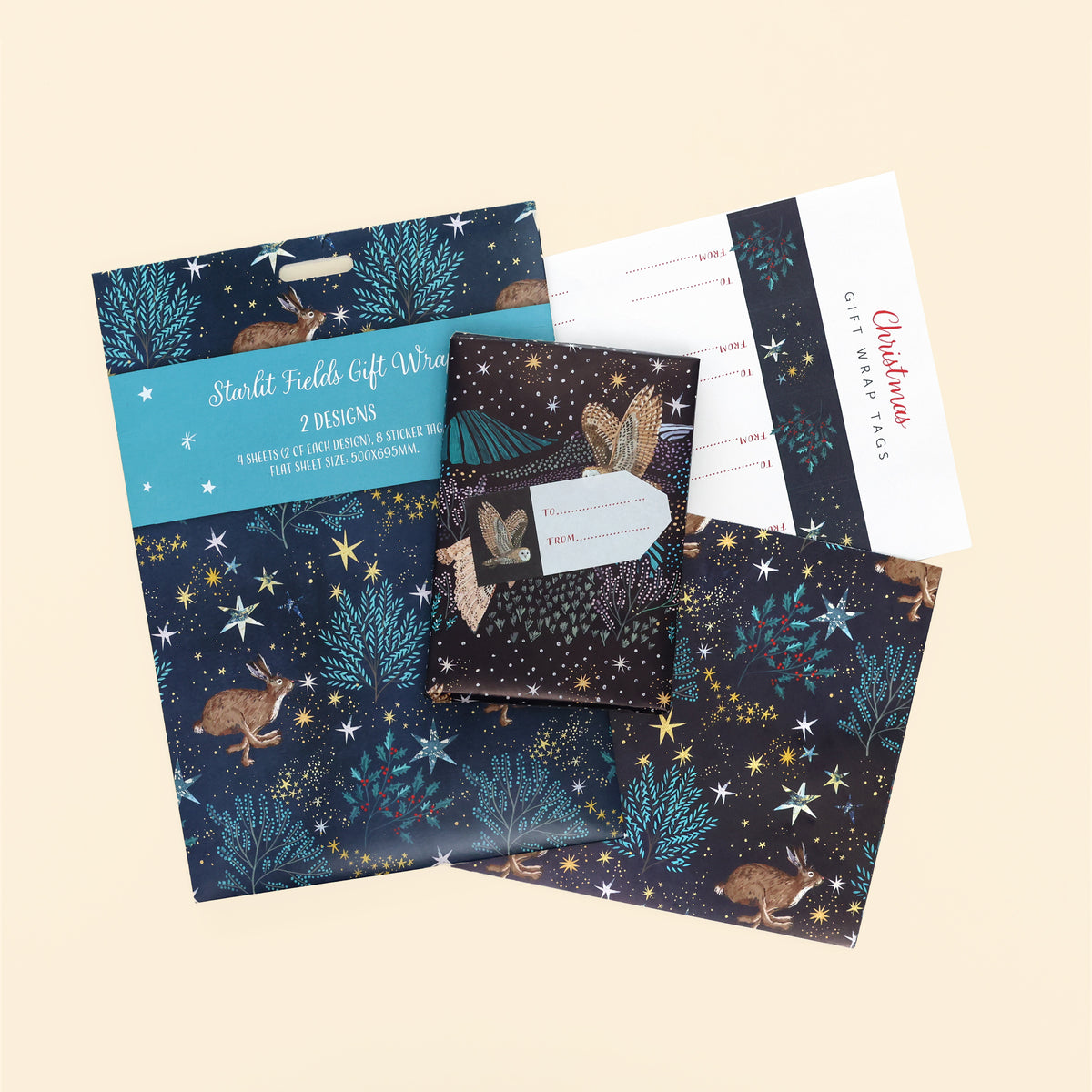 Paper gift wrap in two 'starlit fields' designs, one with a barn owl and one with a hare. With sticker tags laying on cream coloured background