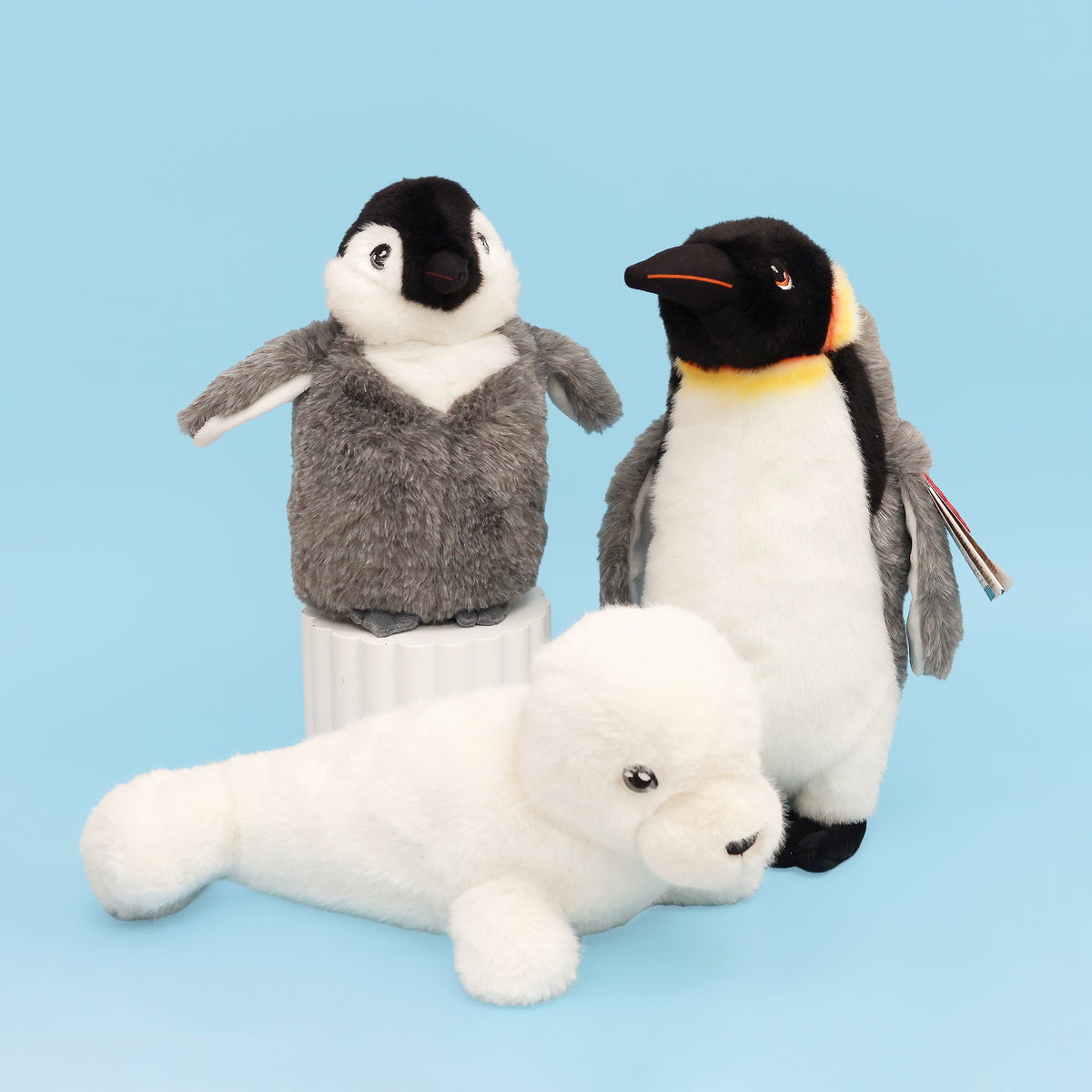 Seal, King emperor and Baby emperor penguin plush as a group on blue background 
