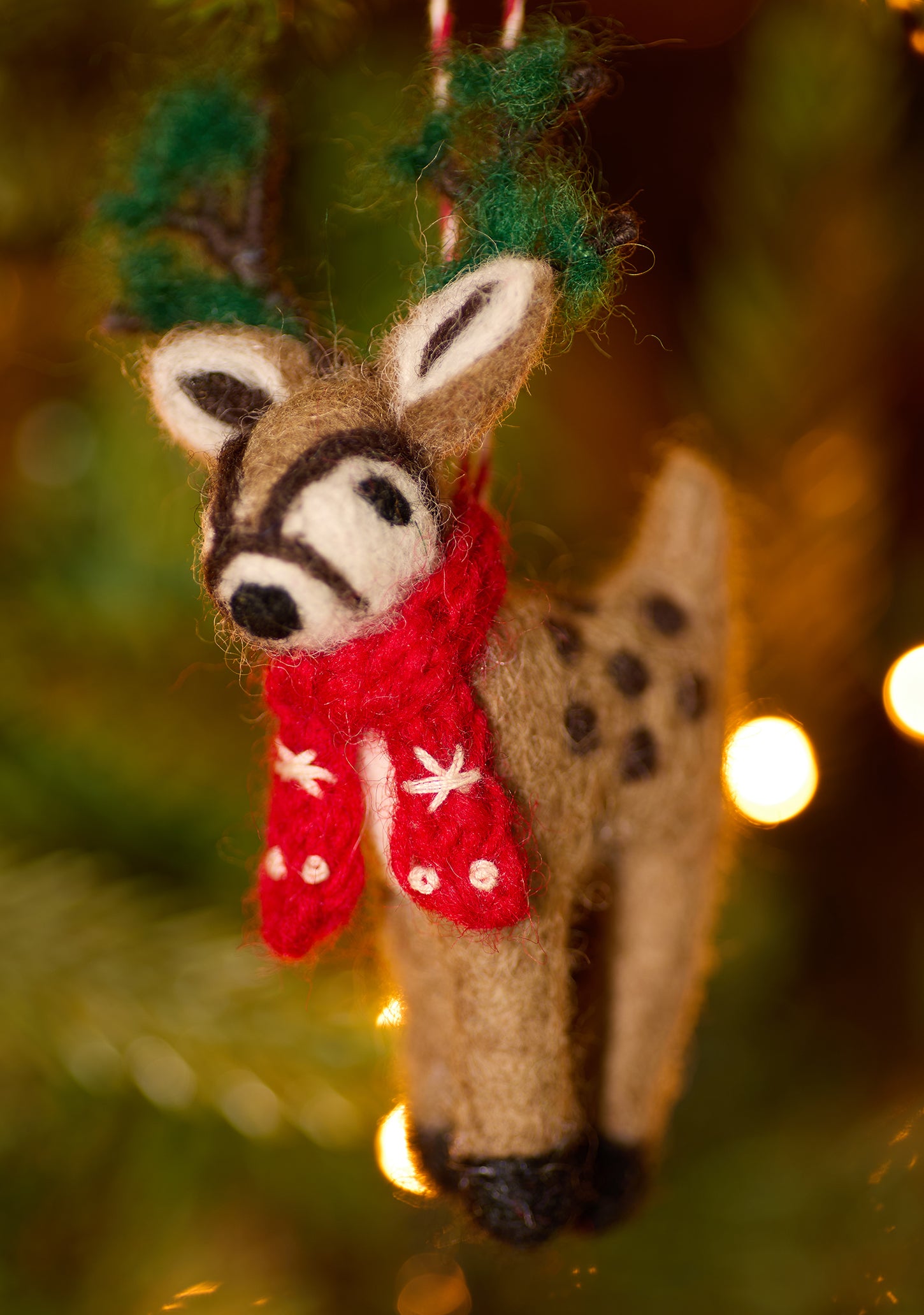 Embroidered Felt reindeer decoration with green antlers and red scarf hanging on tree with lights