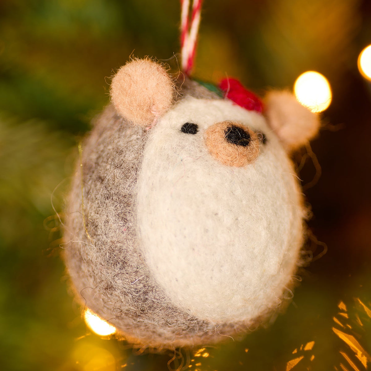 Handmade Felt Hedgehog decoration; round body with small nose, ears and eyes. Handing on a tree from a red and white thread