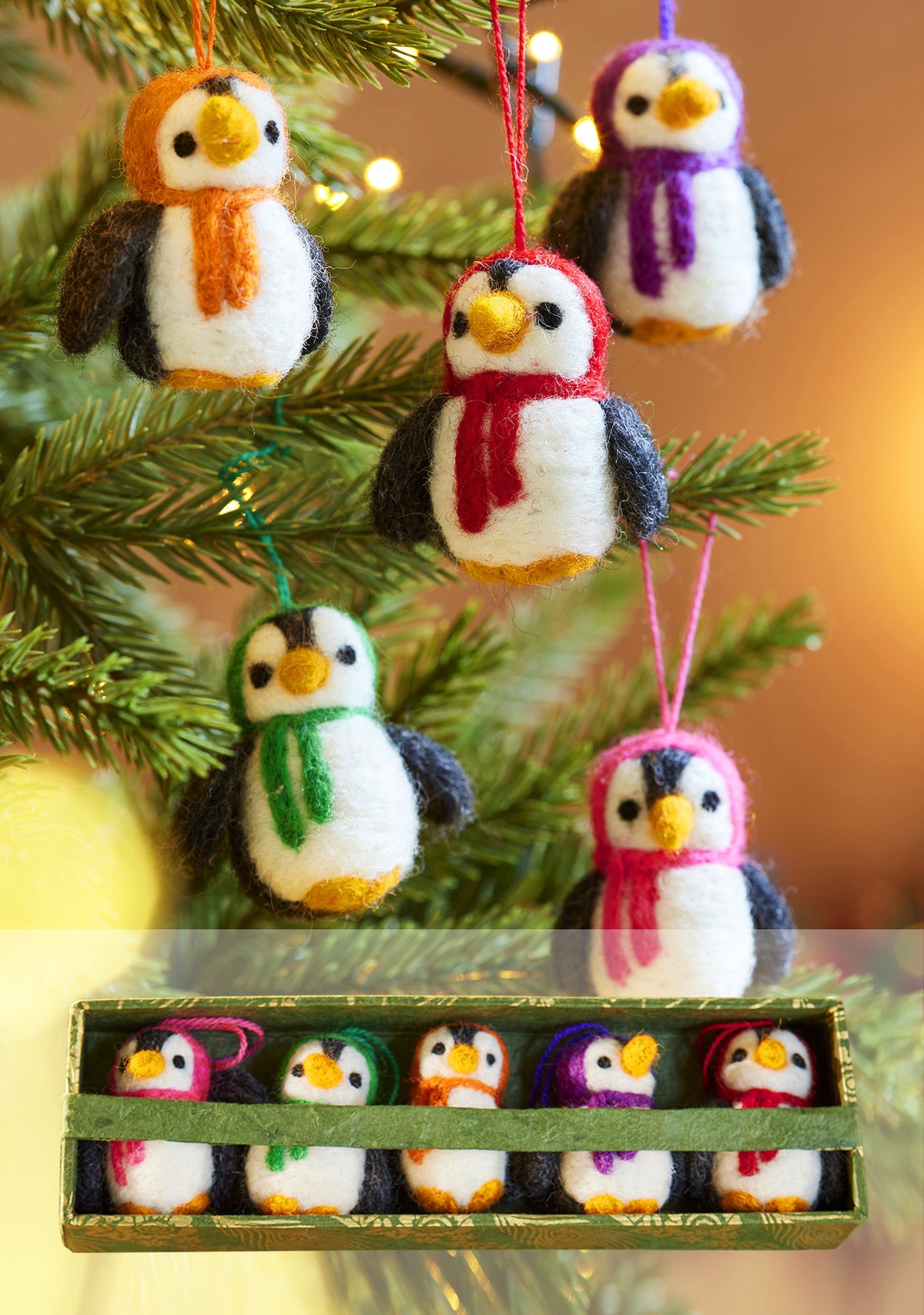 5 handmade felt Penguin tree decorations hanging in tree as a set and presented in a recycled cardboard box with Lokta paper wrap and ribbon