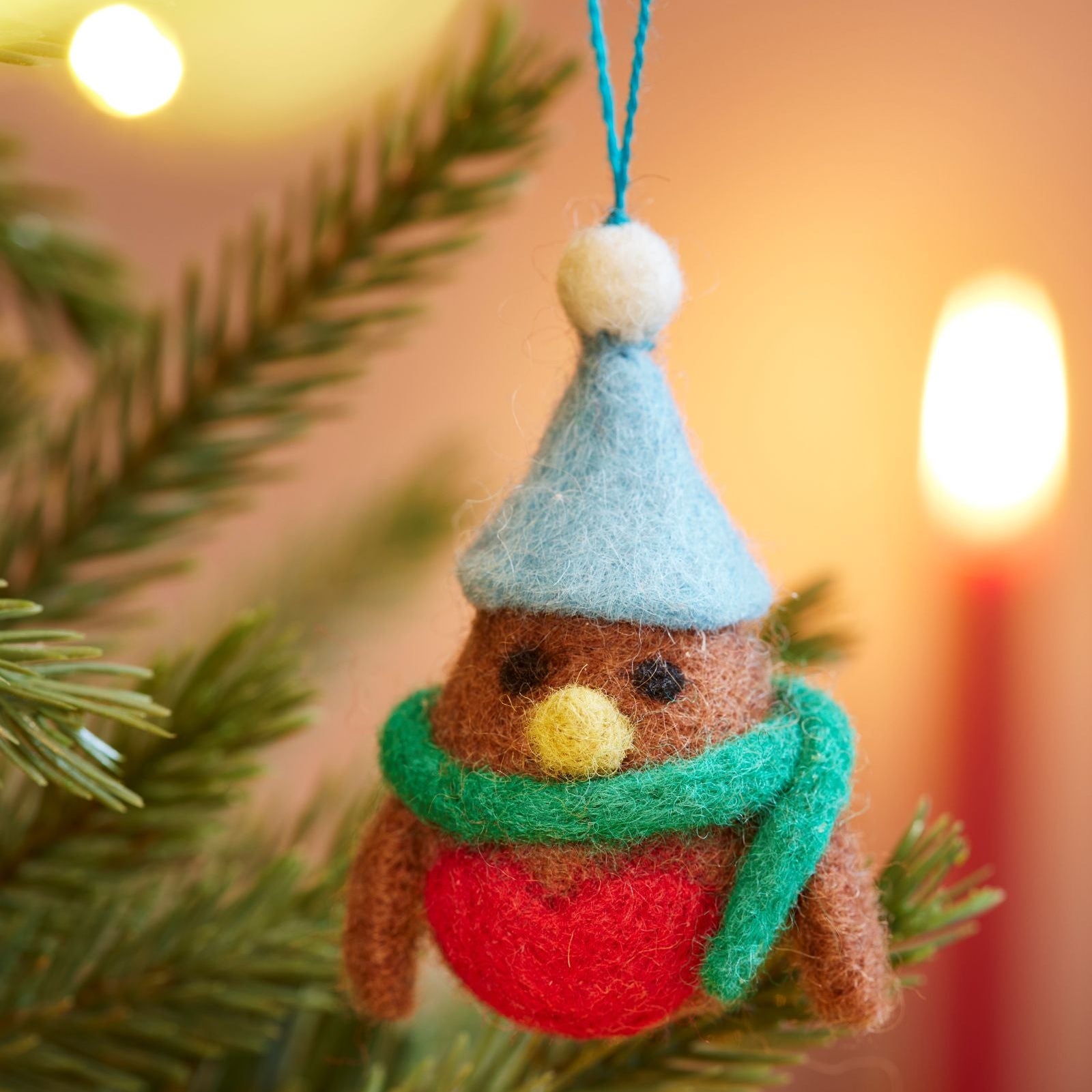 Close up of felt brown robin with blue hat and green scarf hanging in tree