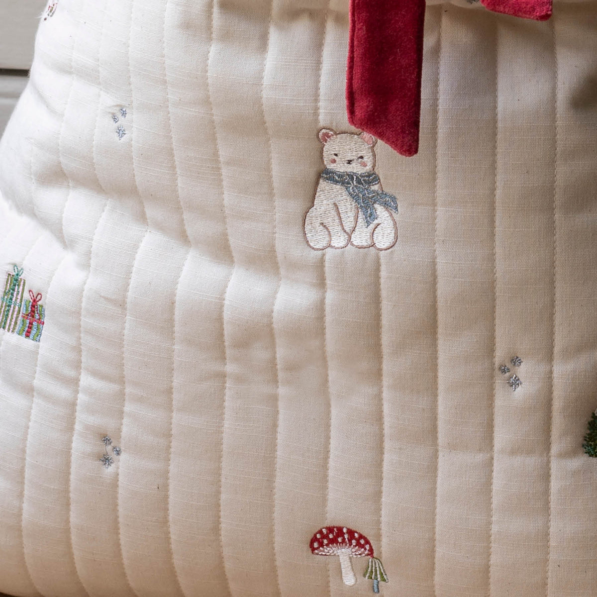 Close up of embroidered polar bear, presents and mushrooms on present sack