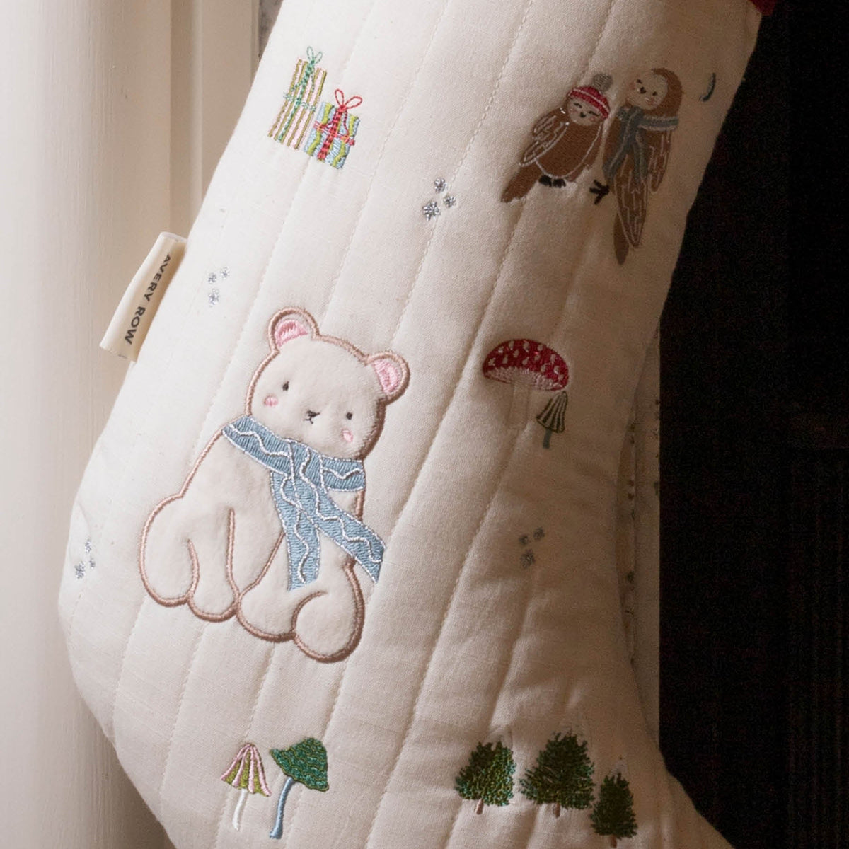 Close up of embroidery of Polar bear, owls, mushrooms, trees and presents on stocking