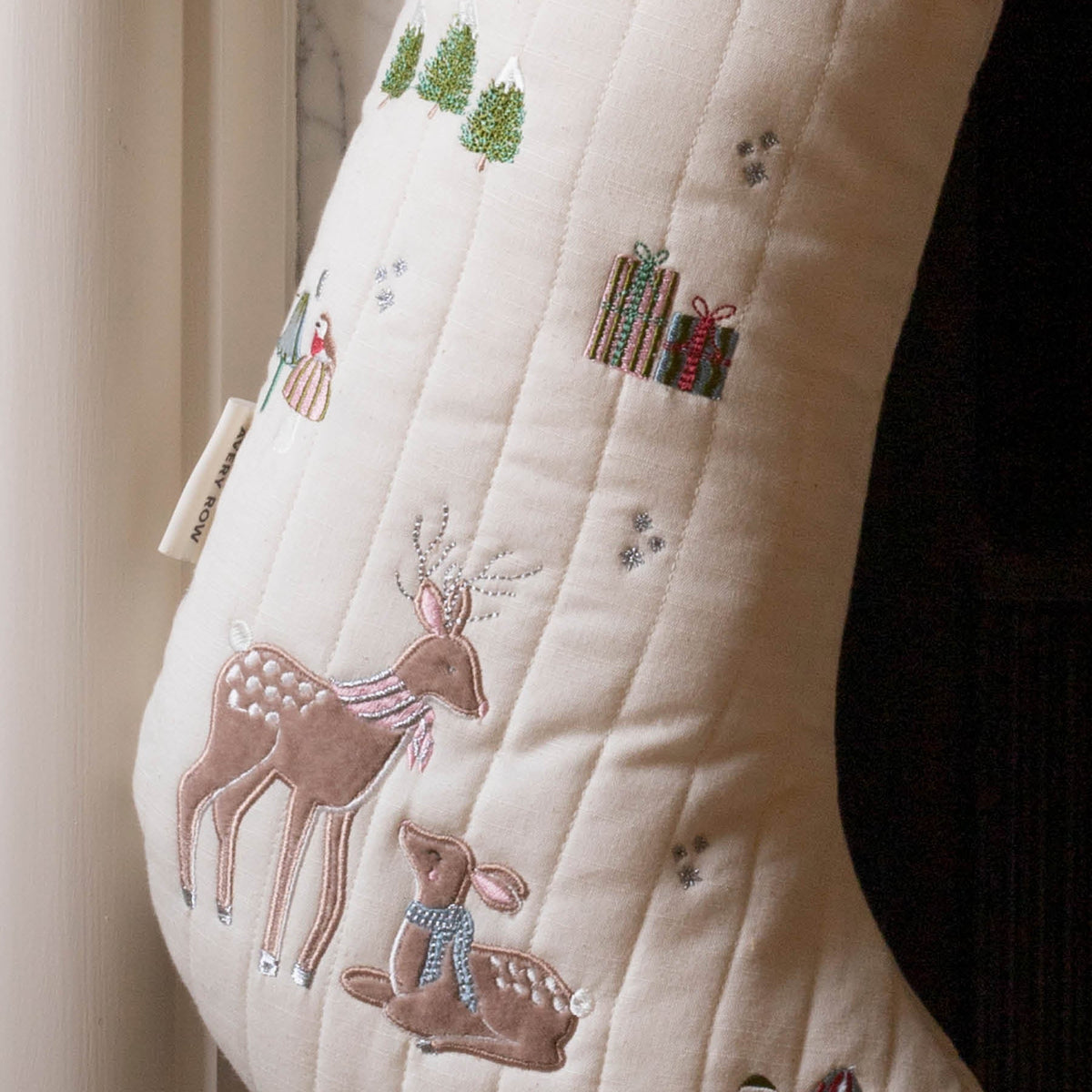 Close up of Reindeers, presents, trees and robin embroidery on stocking, hanging from fireplace