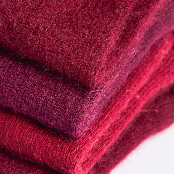 Close up of Recycled cashmere fingerless gloves folded in different tones of berry