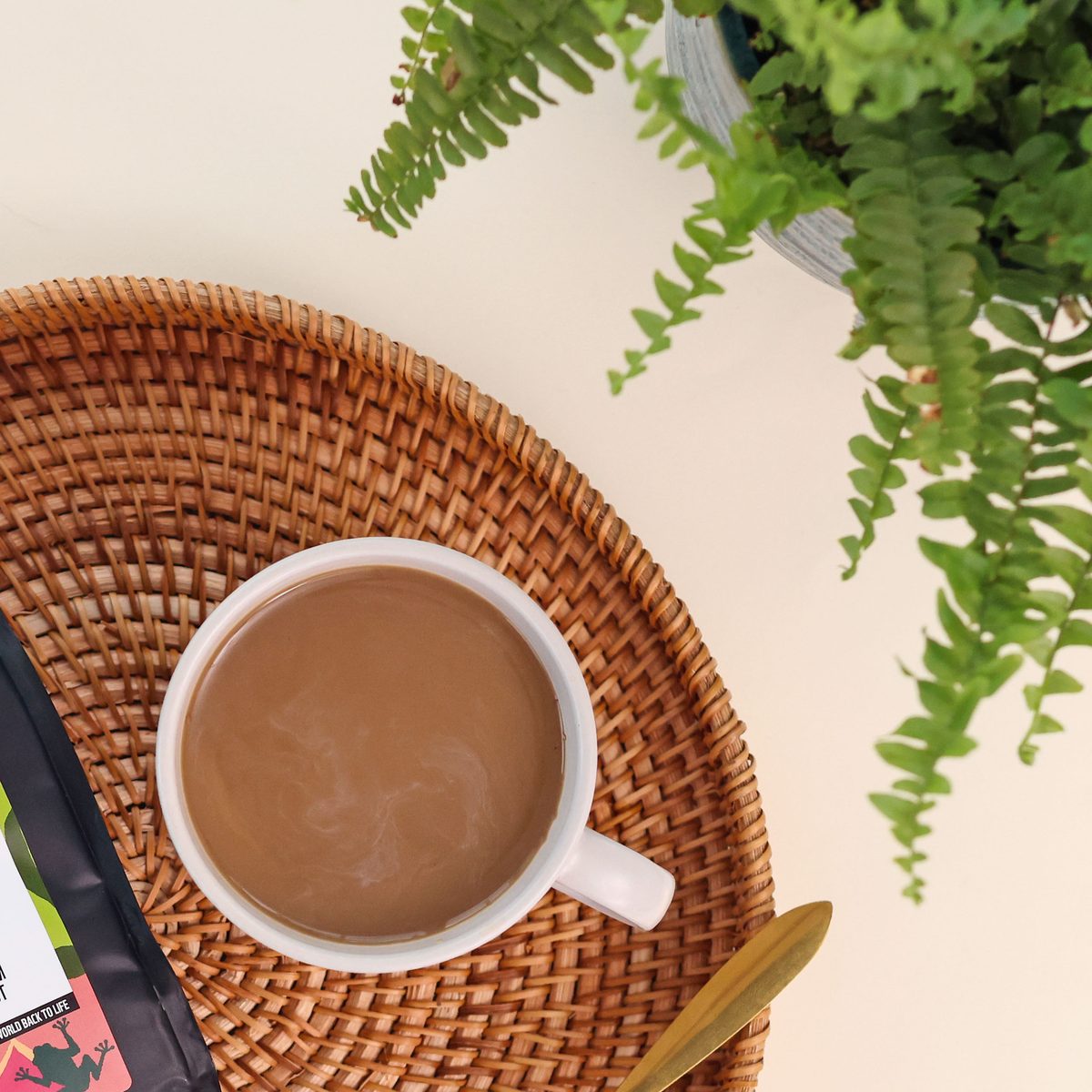 A cup of Earthbrew coffee on a rattan tray beside the bag